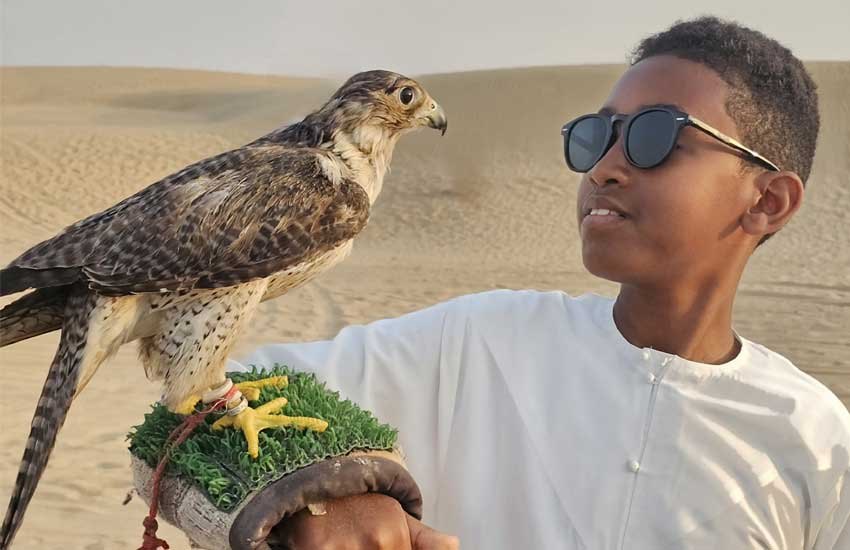 Hayuu Seeroo holding a falcon in the desert